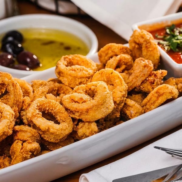 Crispy fried calamari rings and tentacles served with marinara sauce and olive oil with olives.